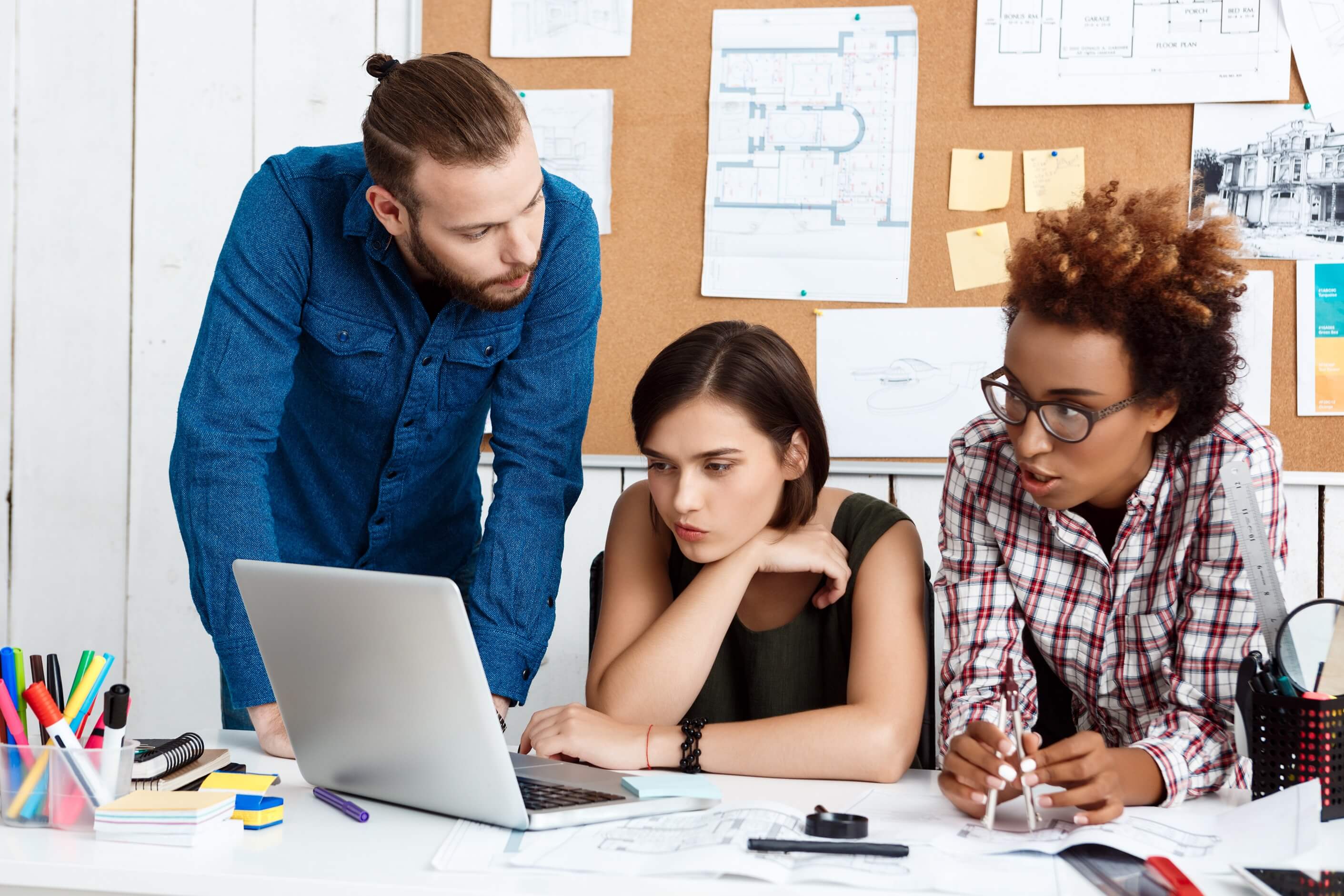 The Kmacims team collaborating around a desk with open laptops